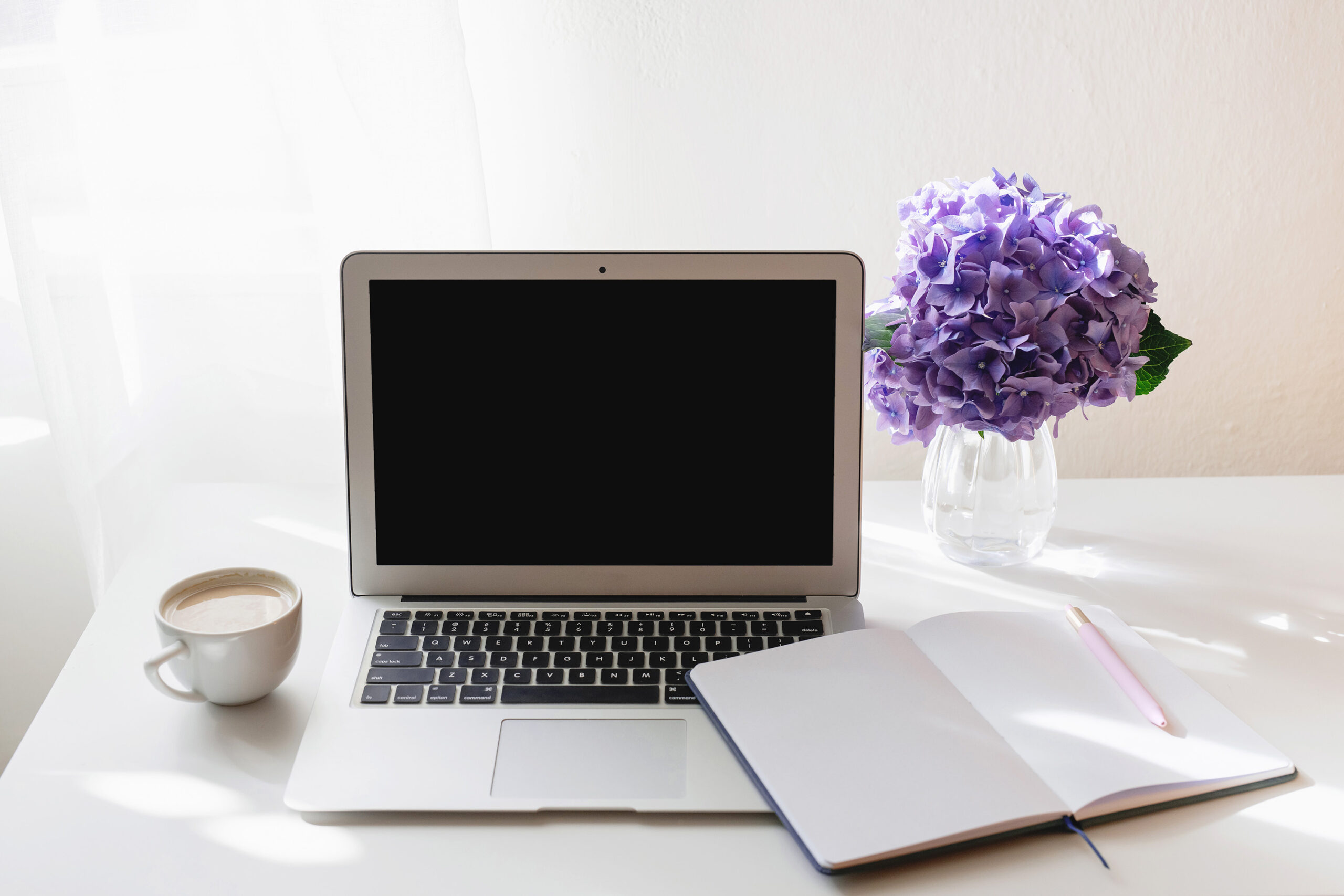 computer and notebook with purple flowers and coffee